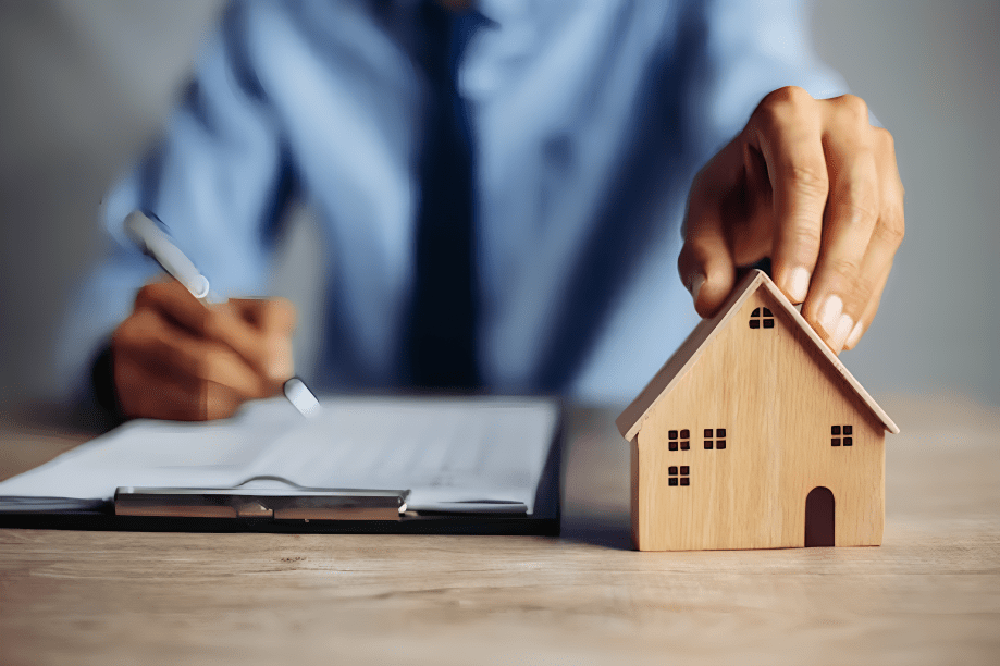 the notary folks provides real estate notary services: Image shows a notary agent signing a document and same time holding a toy house