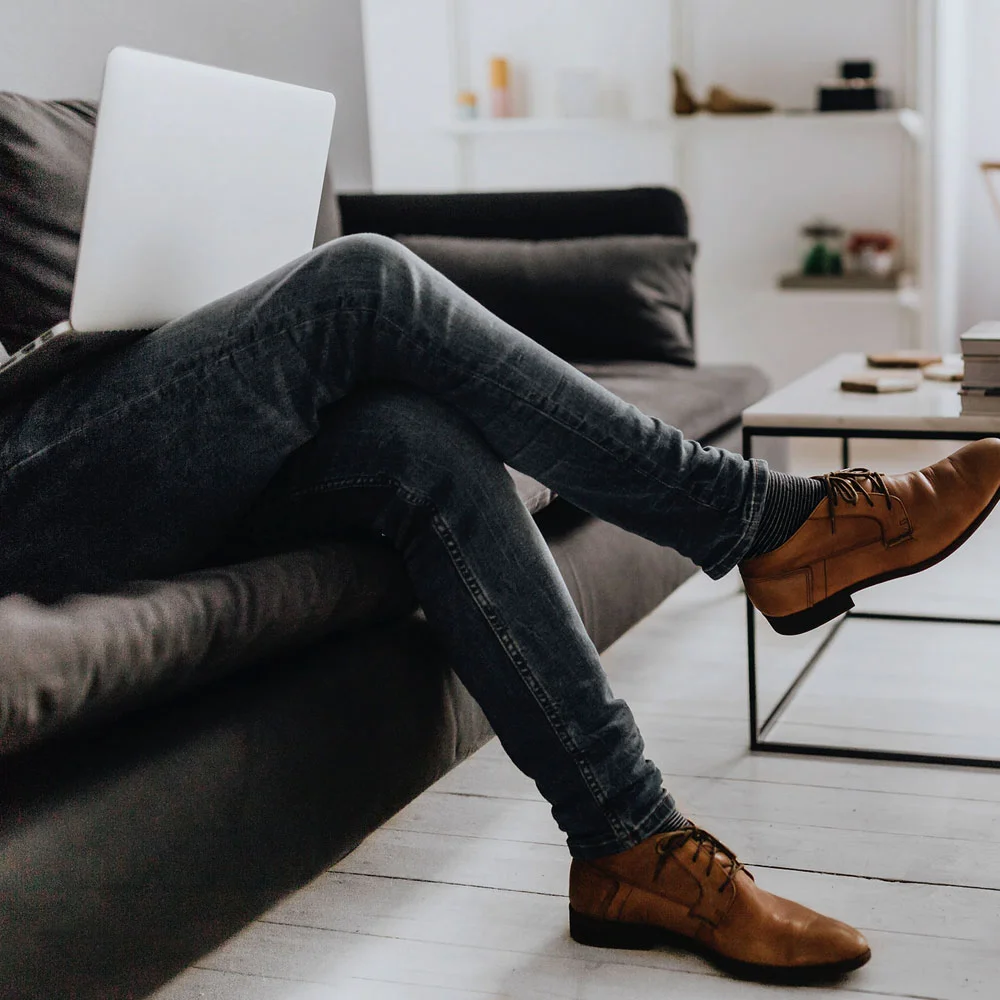 remote online notarization: A man sits comfortably on a chair, one leg crossed over the other, using his laptop to participate in a remote online notarization session.