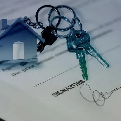 real estate notary: key and toy house on a signing document which is on the table